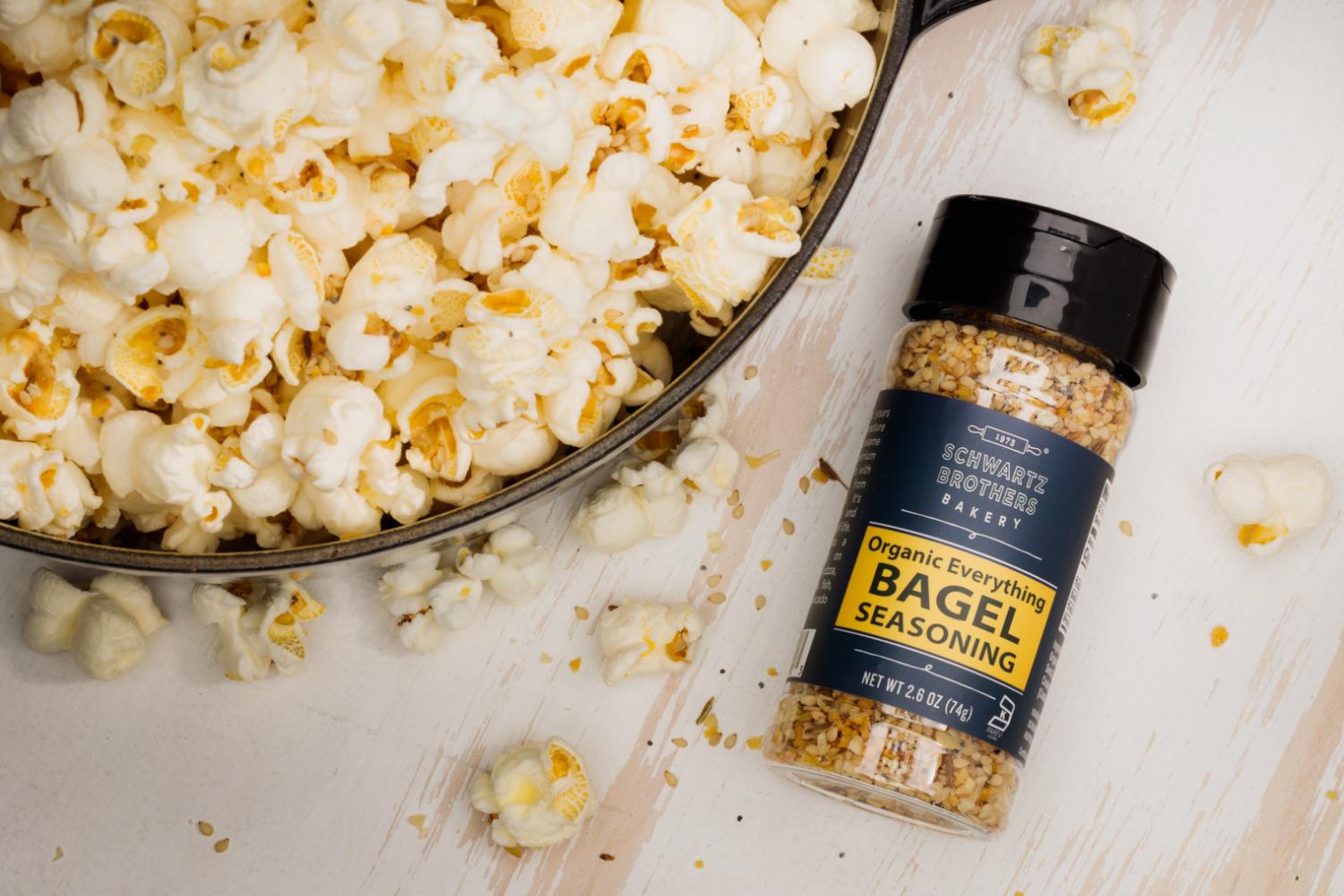 container of Everything Bagel Seasoning next to a bowl of popcorn