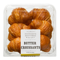 A clear plastic clamshell package of Schwartz Brothers Bakery Butter Croissants on a white background.