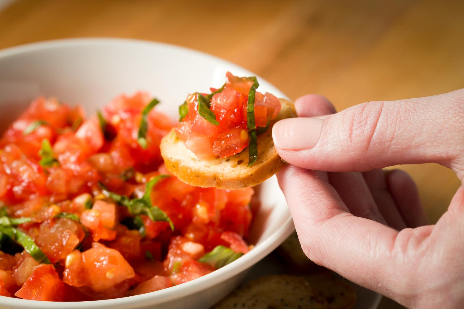 close up of someone dipping Garlic & Herb Bagel Chip in salsa