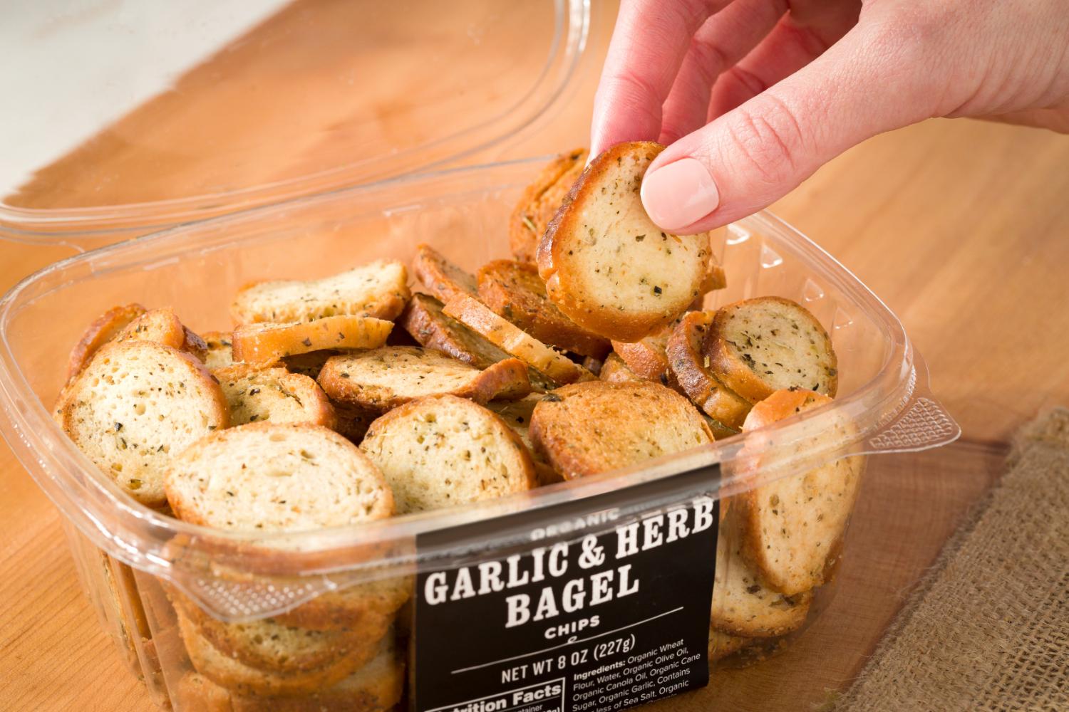 close up of someone pulling a Garlic & Herb Bagel Chip out of the container