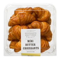 A clear plastic clamshell package filled with golden-brown mini butter croissants, with a white label reading 'Schwartz Brothers Bakery' and 'Mini Butter Croissants' on a white background.